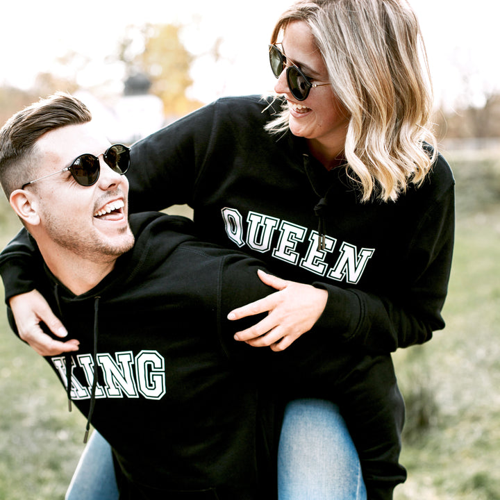 Partnerhoodie für Damen und Herren, junges Paar mit schwarzen Pullover mit der Aufschrift QUEEN und KING